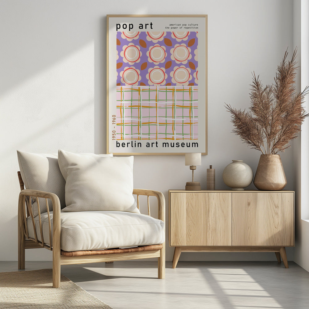 A framed pop art museum poster advertising an exhibition at the Berlin Art Museum. The poster features two distinct patterns. The top section has repeating stylized cream and red flowers on a purple background, with the words 'pop art' and 'american pop culture the power of repetition'. The bottom section displays a pink, green, and orange plaid pattern. The dates '1950 - 1960' are printed vertically on the side. Artwork