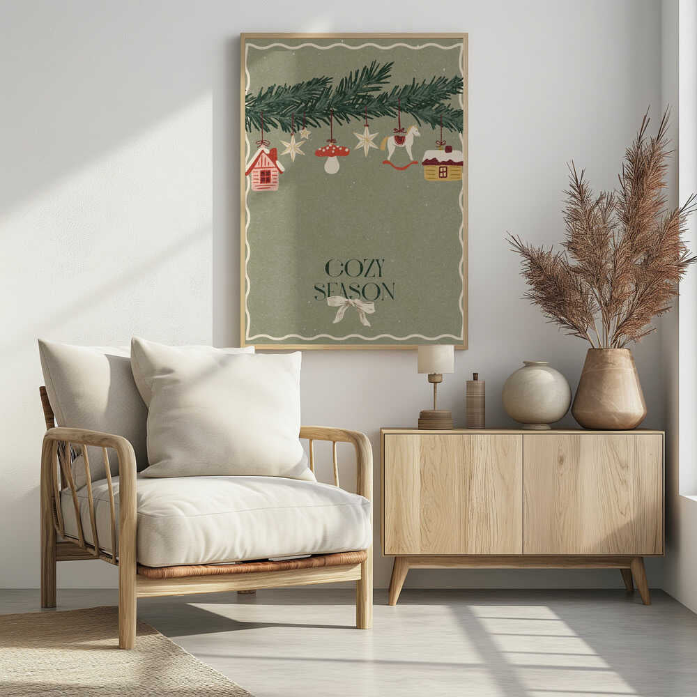 A vintage-style holiday poster with a sage green background. A pine branch hangs at the top, decorated with illustrated ornaments including houses, stars, a mushroom, and a rocking horse. Below, the text 'COZY SEASON' is written in a dark serif font with a light-colored bow underneath. Artwork