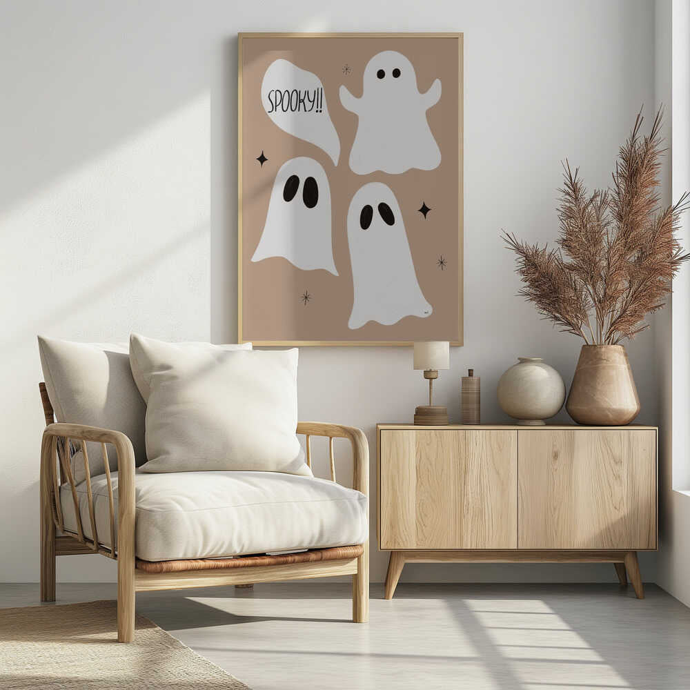 A playful illustration for Halloween featuring three cute, cartoonish white ghosts with black eyes against a solid light brown background. One ghost is accompanied by a speech bubble that reads 'SPOOKY!!' in a hand-drawn font. Small black stars and asterisks are scattered around the ghosts. The artwork is enclosed in a thin black frame. Decor