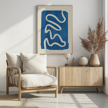 An abstract art piece in a black frame, featuring a solid, textured blue shape on a cream background. A single, thick, meandering white line flows from the top to the bottom within the blue area, creating a simple yet dynamic composition. Decor