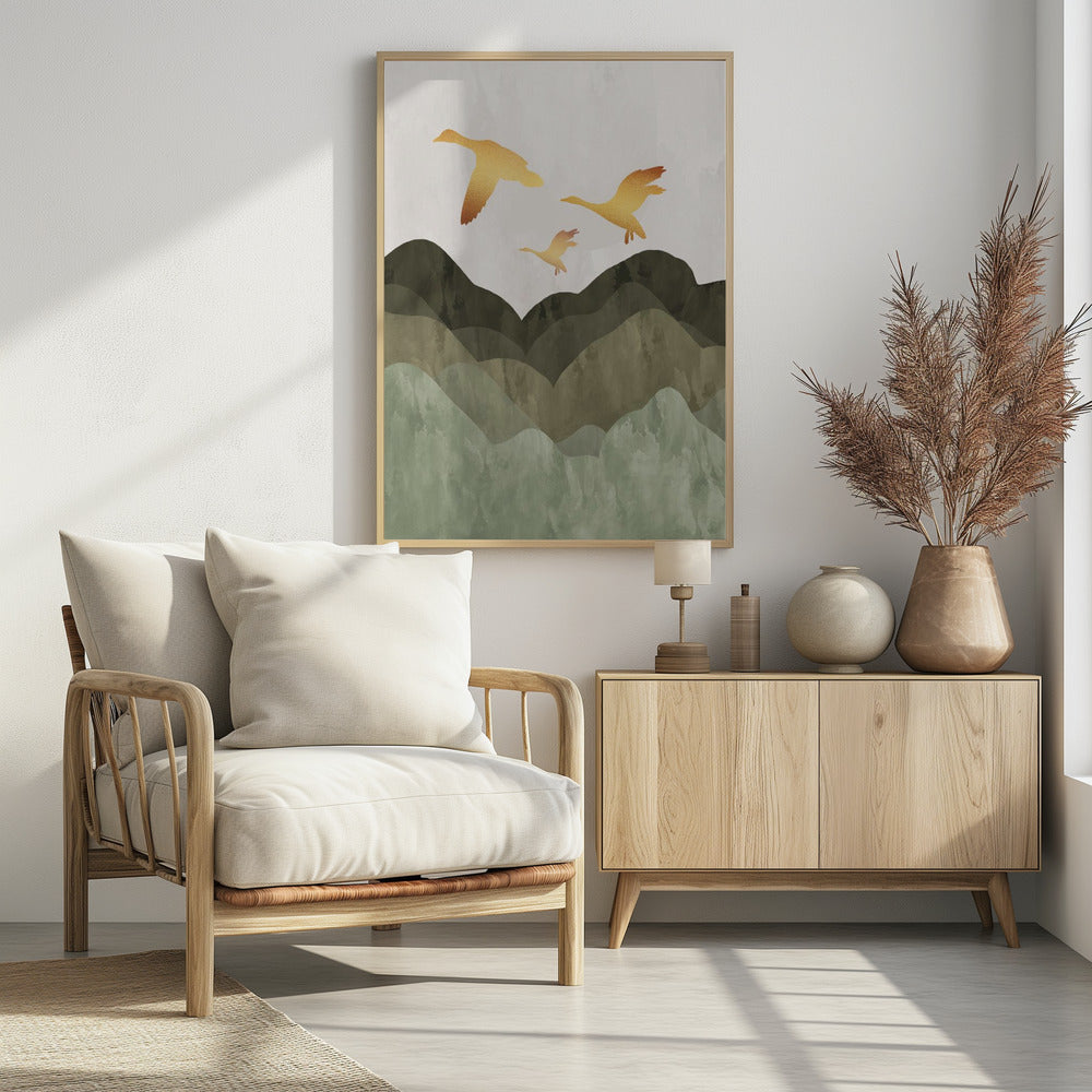 A minimalist art print of three golden bird silhouettes flying over a stylized landscape of layered mountains in muted shades of green and brown, set against a light grey, textured sky and enclosed in a thin black frame. Print