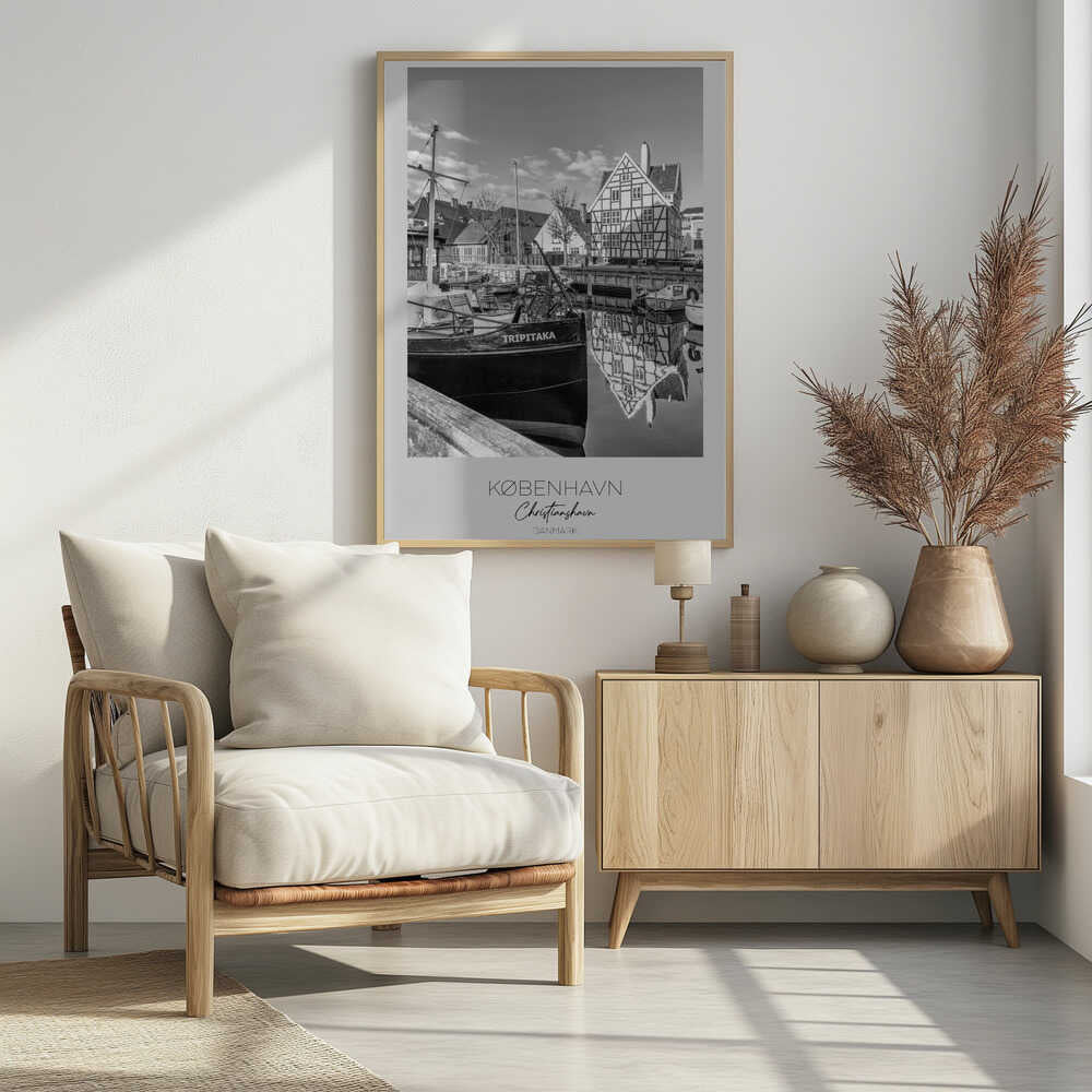 A black and white travel poster featuring a photo of Christianshavn in Copenhagen. The scene shows a boat named 'TRIPITAKA' docked in a canal, with a prominent half-timbered building across the water, its reflection visible on the surface. The bottom of the poster has text that reads 'KØBENHAVN', 'Christianshavn', and 'DANMARK'. Artwork
