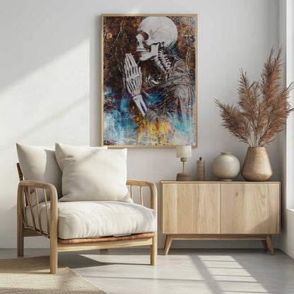 A mixed media artwork of a skeleton from the chest up, in profile, with its hands clasped together in prayer. The background is a heavily textured and cracked dark brown, with abstract splashes of blue and fiery yellow, particularly at the bottom. Wall Art