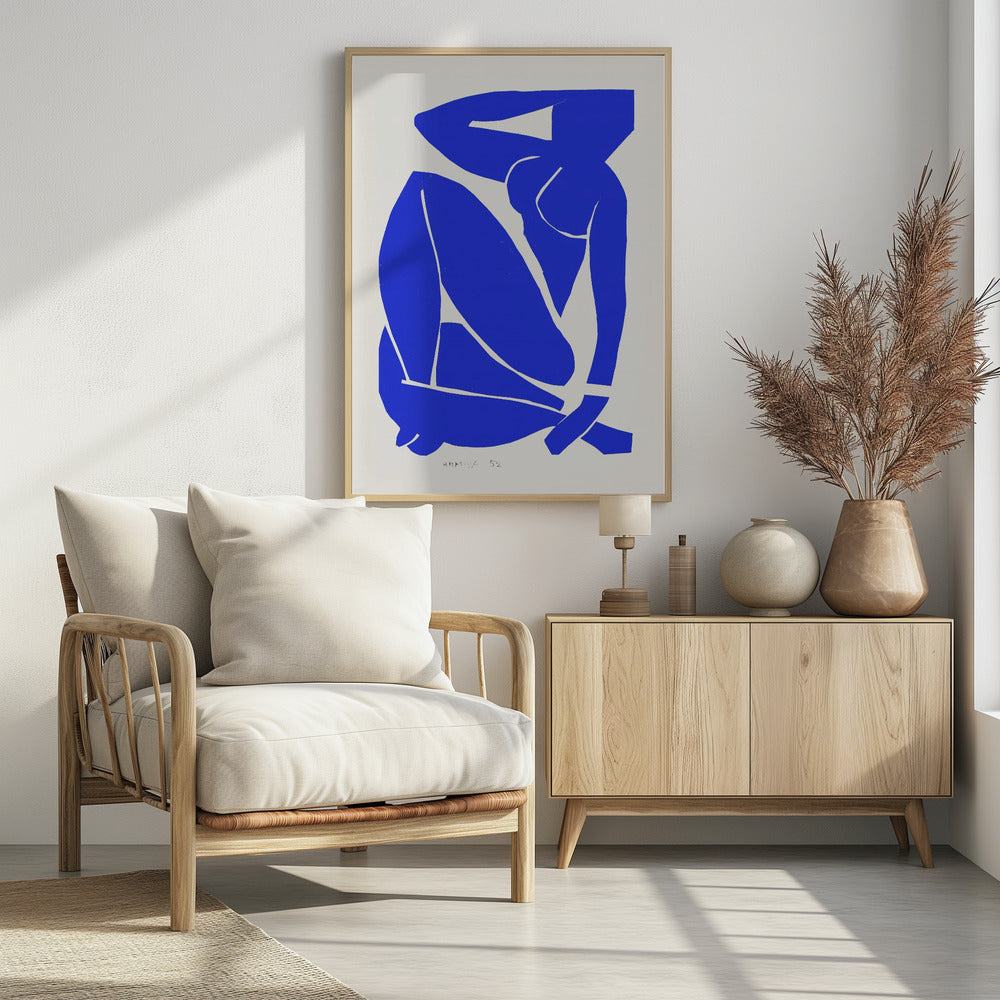 A framed print of Henri Matisse's 'Blue Nude II', featuring a bold, royal blue paper cutout of a seated female nude against an off-white background. The figure is stylized and abstract, with limbs folded and one arm behind her head. Print