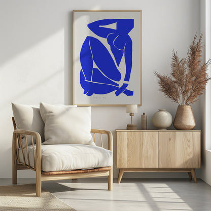 A framed print of Henri Matisse's 'Blue Nude II', featuring a bold, royal blue paper cutout of a seated female nude against an off-white background. The figure is stylized and abstract, with limbs folded and one arm behind her head. Print