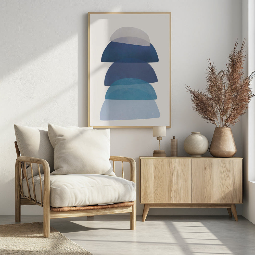 An abstract art print in a black frame, featuring a vertical stack of five semi-circular, dome-like shapes against an off-white background. The shapes are in various shades of blue and gray and have a translucent, overlapping quality, creating a sense of depth and balance. Artwork
