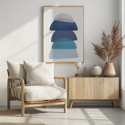 An abstract art print in a black frame, featuring a vertical stack of five semi-circular, dome-like shapes against an off-white background. The shapes are in various shades of blue and gray and have a translucent, overlapping quality, creating a sense of depth and balance. Artwork