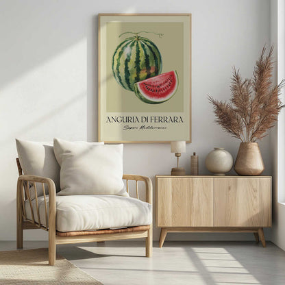A vintage-style food poster in a black frame, featuring a detailed illustration of a whole striped watermelon and a cut slice showing its red flesh and black seeds. The background is a pale cream-green. Below the fruit, the text reads 'ANGURIA DI FERRARA' and 'Sapori Mediterranei'. Print