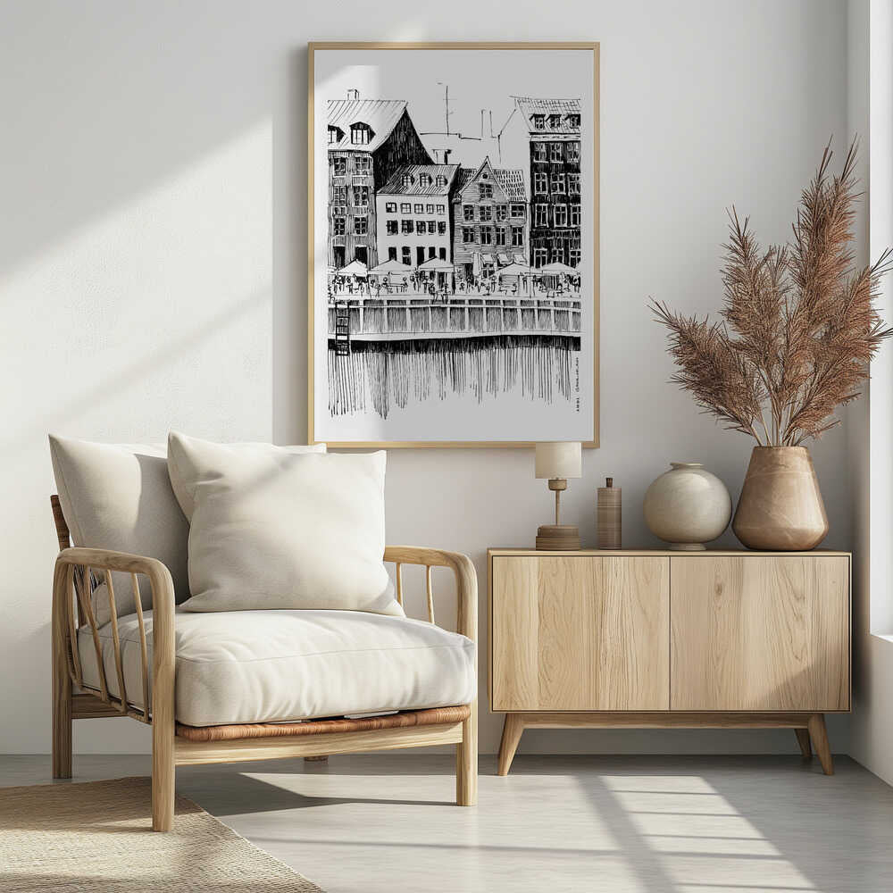 A black and white ink line drawing of a charming European city scene along a canal. Tall, narrow buildings with gabled roofs line the waterfront, in front of which is a bustling pier with outdoor cafes filled with people under umbrellas. The water's reflection is illustrated with simple vertical lines. The artwork is framed in black. Wall Art