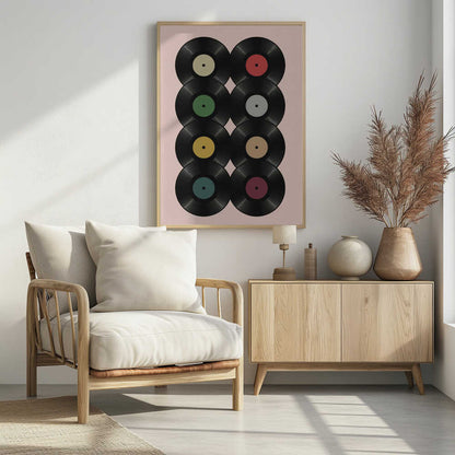 A graphic art print featuring eight black vinyl records arranged in two columns of four against a pale pink background. Each record has a different solid-colored label, creating a colorful and retro pattern. The artwork is enclosed in a simple black frame. Artwork