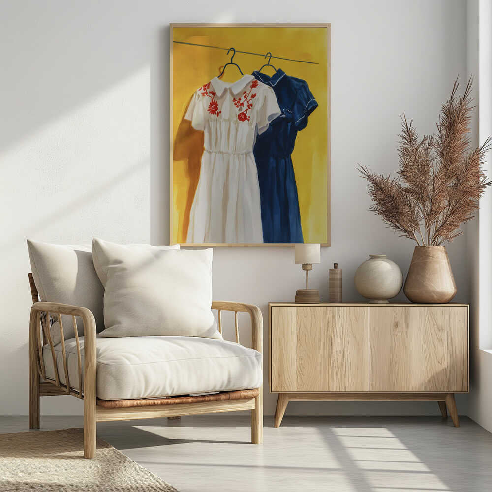 A painting of two vintage-style dresses hanging on a clothesline against a bright yellow wall. The dress in the foreground is white with red floral embroidery on its collar, and the dress behind it is a solid dark blue. Decor
