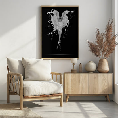 A dramatic black and white photograph of a ballerina suspended in mid-air against a black background. She is en pointe, and a dynamic splash of white liquid surrounds her, creating the illusion of wings. Artwork