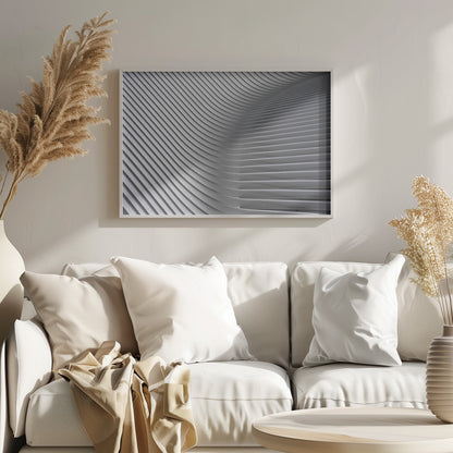 A framed, close-up, abstract photograph of a modern architectural structure. Parallel white ribs curve and undulate across the frame, creating a sense of movement and rhythm through the interplay of light and shadow. Artwork