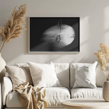 A dramatic black and white framed photograph of a female figure skater performing on ice. She is illuminated by a single spotlight, holding a graceful standing split pose, with her reflection visible on the ice below. Poster