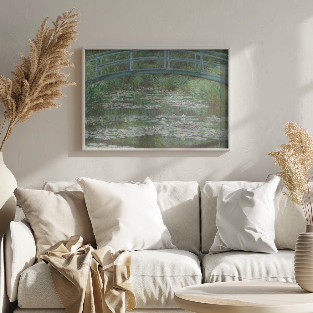 An Impressionist painting by Claude Monet depicting a green Japanese-style footbridge arching over a tranquil pond filled with blooming water lilies and lily pads, all rendered in soft, dappled brushstrokes and framed in a modern silver frame. Print