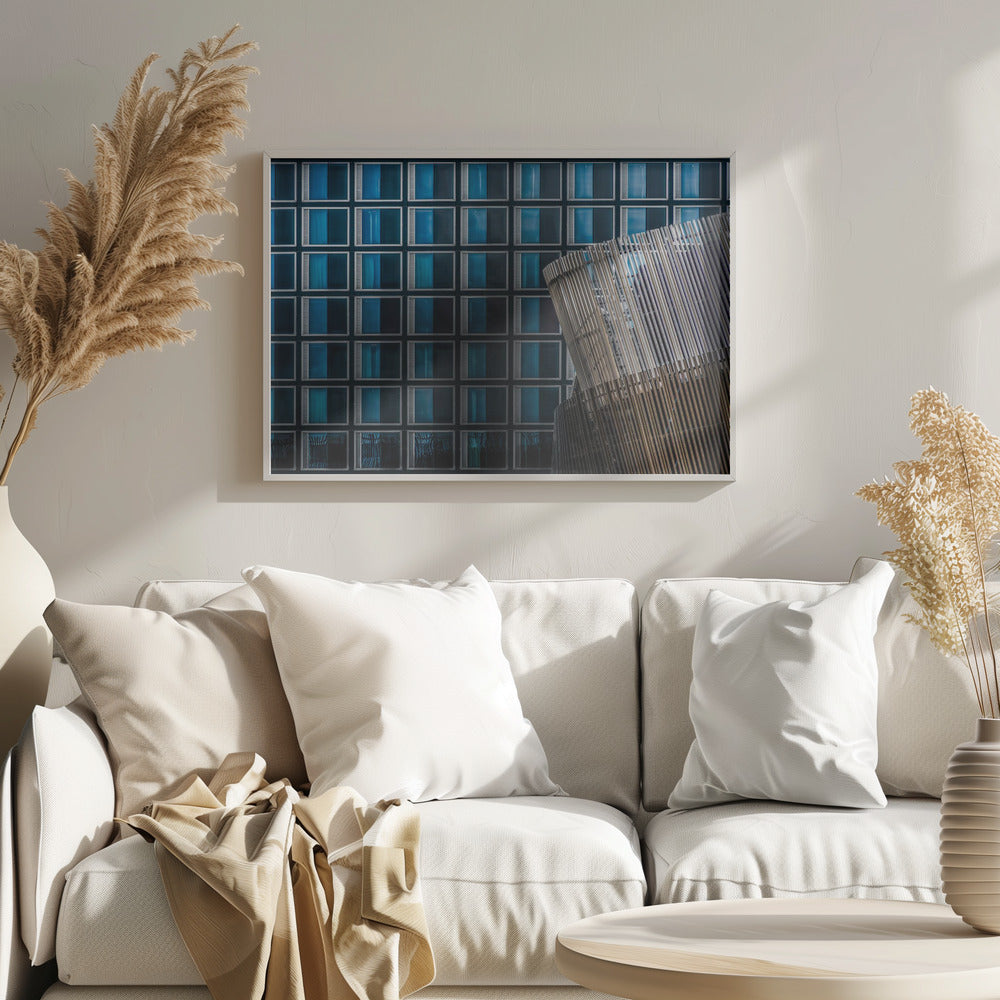 An architectural abstract photograph featuring a modern building facade with a grid of blue and black square windows, contrasted by a curved, slatted structure in the foreground, all enclosed in a silver frame. Wall Art