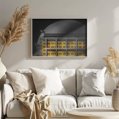 A framed architectural photograph with selective color, featuring a bright yellow building in the foreground against a monochrome background of a large grey dome structure under a black sky. Wall Art