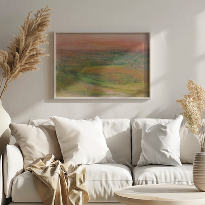 An abstract landscape painting in a silver frame. The artwork features a warm, peachy-orange sky above a rolling terrain of muted greens, yellows, and oranges. A faint, winding path meanders through the landscape, rendered in a soft, impressionistic style. Artwork
