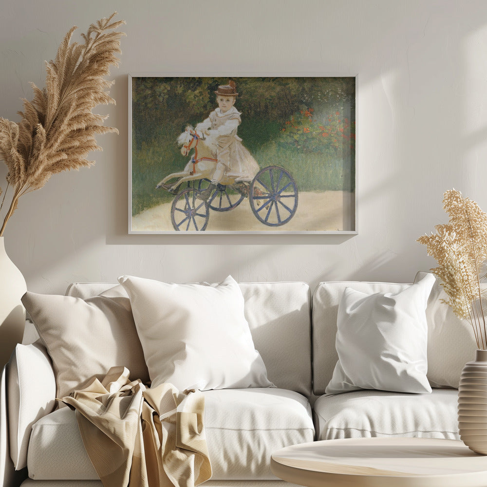 An Impressionist painting by Claude Monet depicting his son, Jean, riding a toy horse tricycle. The young boy wears a brown hat and a light-colored outfit, sitting on a white hobby horse with large blue wheels, set against a lush green garden background. Decor