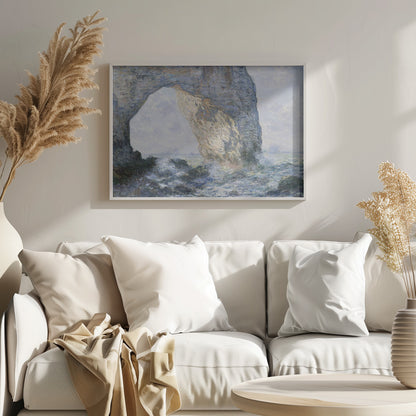 An impressionist painting by Claude Monet of the Manneporte rock arch at Étretat, France. Sunlight illuminates the massive stone arch as turbulent blue and white waves crash against the rocky shoreline below. The artwork is displayed in a silver frame. Decor