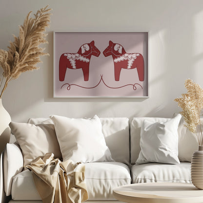 A symmetrical illustration of two red Swedish Dala horses facing each other against a light pink background. The horses are decorated with intricate white and pink folk art patterns. The artwork is presented within a silver frame. Artwork