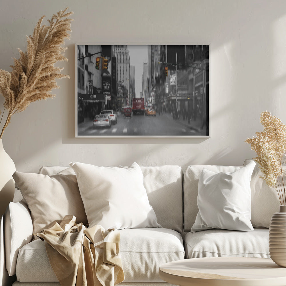 A framed, stylized photograph of a busy New York City street, presented mostly in black and white with a motion blur effect. Pops of color highlight red vehicles and yellow traffic lights, drawing focus down the urban canyon lined with skyscrapers and Broadway signs. Decor