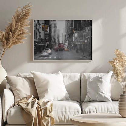 A framed, stylized photograph of a busy New York City street, presented mostly in black and white with a motion blur effect. Pops of color highlight red vehicles and yellow traffic lights, drawing focus down the urban canyon lined with skyscrapers and Broadway signs. Decor