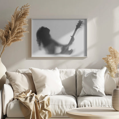 A framed, black and white photograph showing the blurry silhouette of a rock guitarist with long curly hair, head thrown back in passion while holding an electric guitar against a stark white background. Poster