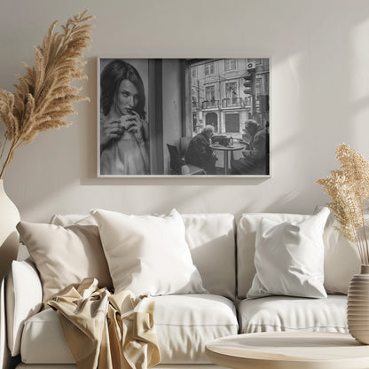 A framed, black and white photograph capturing a scene of juxtaposition. On the left, a large poster shows a glamorous young woman holding a coffee cup. On the right, seen through a cafe window, an elderly couple sits at a small table, also with coffee cups, engaged in conversation against a backdrop of an old European city street. Poster