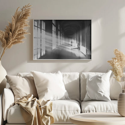 A black and white photograph of a woman walking away down a long, dark hallway. Bright shafts of sunlight pour through large windows on the left, creating a dramatic interplay of light and shadow on the floor and walls. Poster