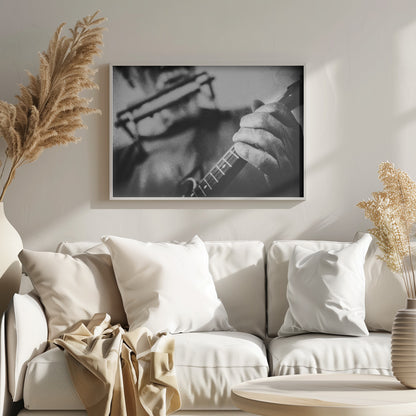 A grainy, black and white close-up photograph of a musician's hand gripping the neck of a stringed instrument. The focus is on the hand and the frets, with the musician's body and face softly blurred in the background. The image is enclosed in a silver frame. Wall Art