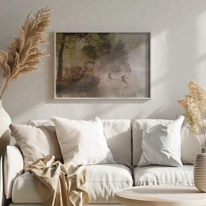 Two geese flying low over a misty forest lake at dawn, a serene nature photograph.