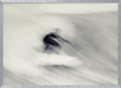 An artistic black and white photograph using motion blur to capture a surfer in a dynamic, fluid pose on a wave. The slow shutter speed creates a sense of speed and abstract movement, with the surfer's dark wetsuit contrasting against the white, streaked water. The image is presented in a silver frame. Decor