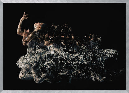 A conceptual piece of artwork depicting a woman in a dynamic pose against a solid black background. Her form appears to be shattering and dissolving into a swirling cloud of broken glass shards, creating a powerful and dramatic effect. The piece is presented within a simple silver frame. Print