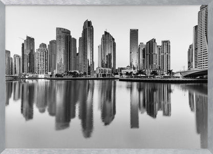 A framed black and white photograph of the Dubai Marina skyline, with its modern skyscrapers perfectly reflected in the calm water of the canal. Decor