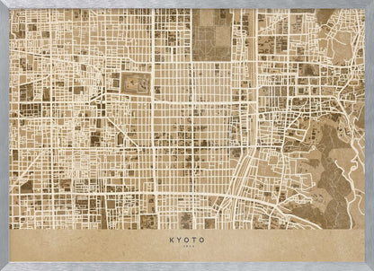 A framed, stylized map of Kyoto, Japan, in shades of brown and beige. The city streets are illustrated as a complex grid of off-white lines against a textured brown background. At the bottom, a solid beige banner contains the text 'KYOTO' and 'JAPAN' in a modern sans-serif font. The artwork is surrounded by a brushed silver frame. Artwork