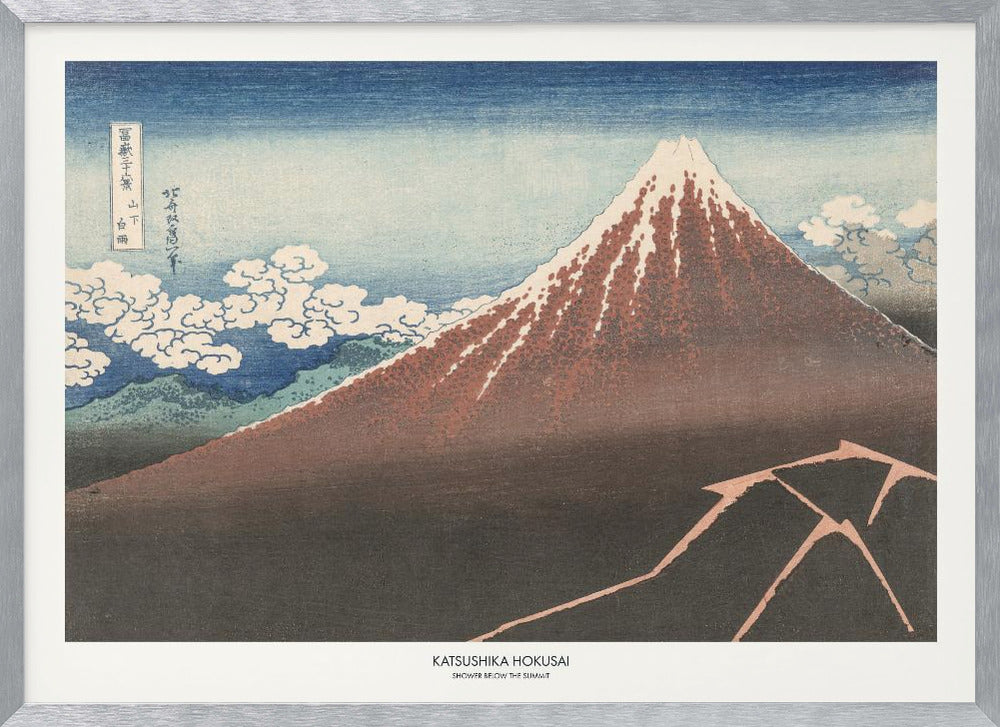 A framed Japanese woodblock print by Katsushika Hokusai titled 'Shower Below the Summit.' The print depicts a large, dark brown and reddish mountain, likely Mount Fuji, with a snow-capped peak. The sky above is a deep blue, and stylized white clouds are scattered around the mountain's slope. In the dark foreground, a jagged pink line represents a lightning strike. Artwork