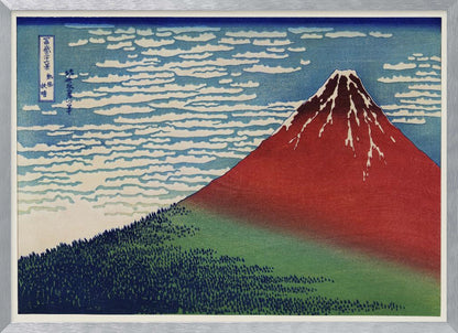 A Japanese woodblock print, Hokusai's 'Fine Wind, Clear Morning', showing a large, reddish-brown Mount Fuji with snow at its peak. Below the mountain is a dense green forest, and above is a blue sky with rows of white, stylized clouds. Print