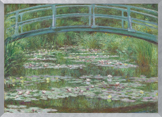 An Impressionist painting by Claude Monet depicting a green Japanese-style footbridge arching over a tranquil pond filled with blooming water lilies and lily pads, all rendered in soft, dappled brushstrokes and framed in a modern silver frame. Print