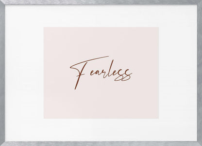 A framed artwork featuring the word 'Fearless' in a flowing brown script font on a pale pink background. The piece is surrounded by a white mat and a textured silver frame. Wall Art