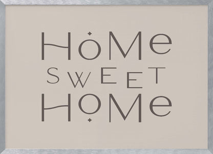 A minimalist wall art piece with the words 'Home Sweet Home' in a dark gray, stylized sans-serif font against a light beige background, all housed within a simple silver frame. Decor