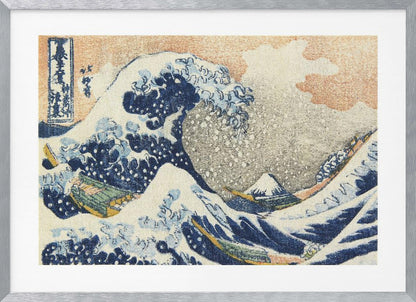 A framed print of Hokusai's 'The Great Wave off Kanagawa,' a Japanese ukiyo-e woodblock print. A huge, dark blue wave with white foam crests over small boats, with a snow-capped Mount Fuji in the distance under a pale orange sky. Artwork