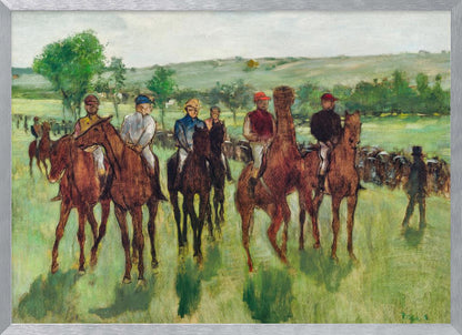 An impressionist painting by Edgar Degas titled 'The False Start', depicting a group of jockeys on their racehorses in a verdant field. The riders are dressed in colorful caps and silks, waiting against a backdrop of rolling green hills and a pale sky. The artwork is displayed in a modern silver frame. Artwork