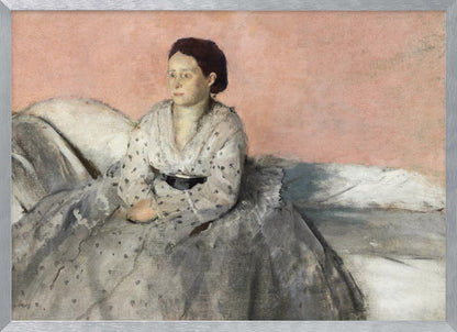 A framed impressionist painting titled 'Mélancolie' by Edgar Degas, depicting a woman with dark hair pulled back, seated on a couch or bed. She wears a white and grey polka-dotted dress with a black sash and has a pensive expression, looking off to the side against a soft pink background. Decor