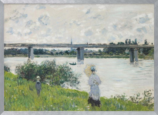 A scenic landscape art print by Claude Monet titled 'The Promenade With the Railroad Bridge, Argenteuil', depicting people on a promenade alongside a body of water with a railroad bridge in the background, characteristic of Impressionist style with soft colors and brushstrokes. Print