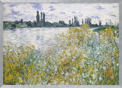 An impressionist landscape painting of a riverbank covered in yellow and white wildflowers. A calm river reflects the cloudy sky, and the opposite bank is lined with tall, dark poplar trees. The artwork is displayed in a silver frame. Artwork