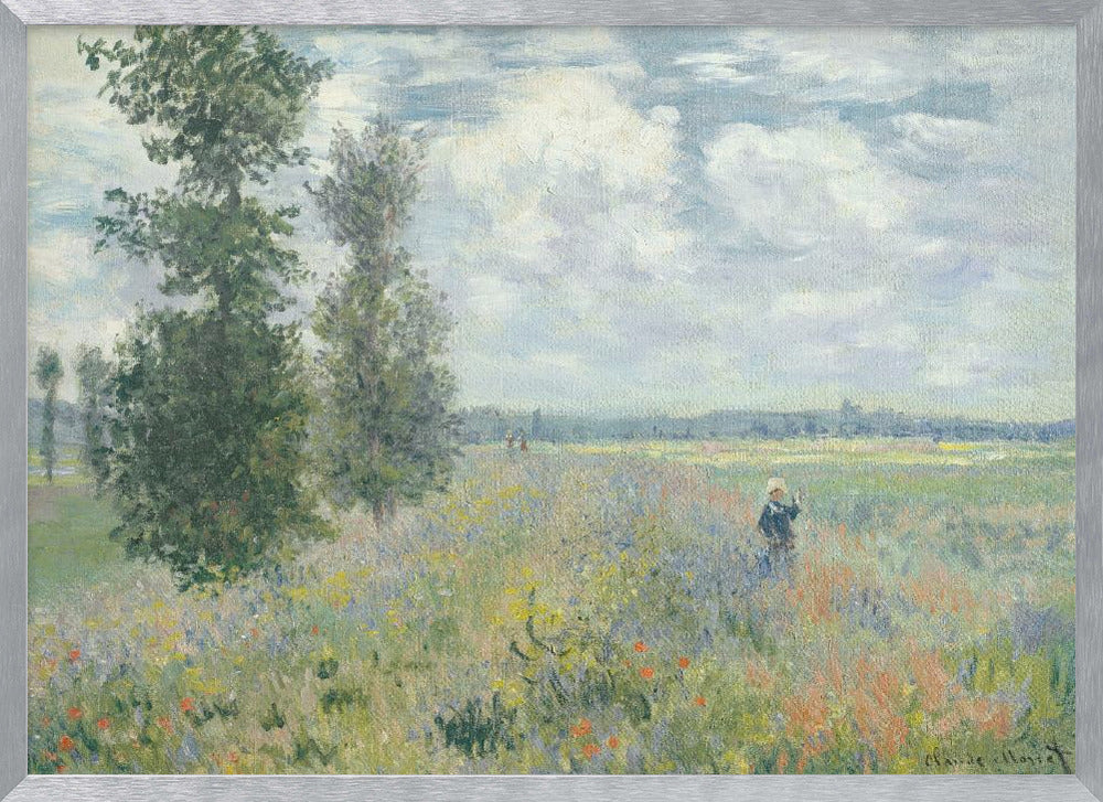 An impressionist painting by Claude Monet titled 'Poppy Field near Vétheuil', depicting a vast field of green grass dotted with red, yellow, and purple wildflowers. A figure in a white bonnet stands in the field to the right. Tall green trees are on the left, under a blue sky with fluffy white clouds. The entire scene is presented within a modern silver frame. Wall Art