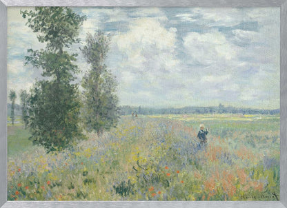 An impressionist painting by Claude Monet titled 'Poppy Field near Vétheuil', depicting a vast field of green grass dotted with red, yellow, and purple wildflowers. A figure in a white bonnet stands in the field to the right. Tall green trees are on the left, under a blue sky with fluffy white clouds. The entire scene is presented within a modern silver frame. Wall Art