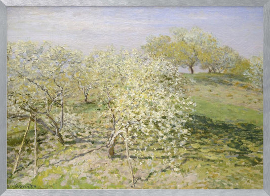 An impressionist painting of an orchard in full bloom, with white and yellow blossoms covering the trees. The orchard is set on a rolling green hillside under a pale, hazy sky, with soft shadows cast on the grass. The artwork is presented in a silver frame. Wall Art
