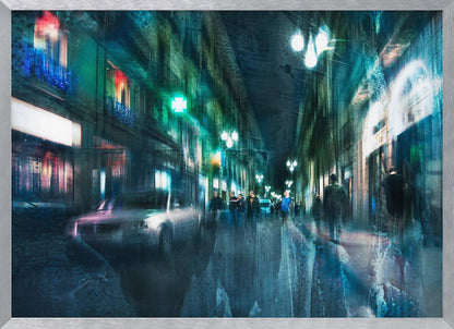 An abstract, moody artwork of a busy city street at night, viewed as if through a rainy window or with motion blur. The scene is dominated by shades of deep blue and vibrant green, with glowing streetlights and neon signs casting reflections on the wet pavement. Silhouettes of people walk down the street, and a car is partially visible on the left. The entire composition has a dynamic, dreamlike quality and is presented in a silver frame. Poster
